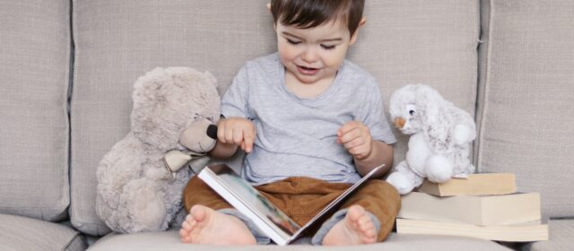 🌟Nominated!🌟 Cute happy little baby boy reading book sitting on sofa with teddy bear and rabbit toy